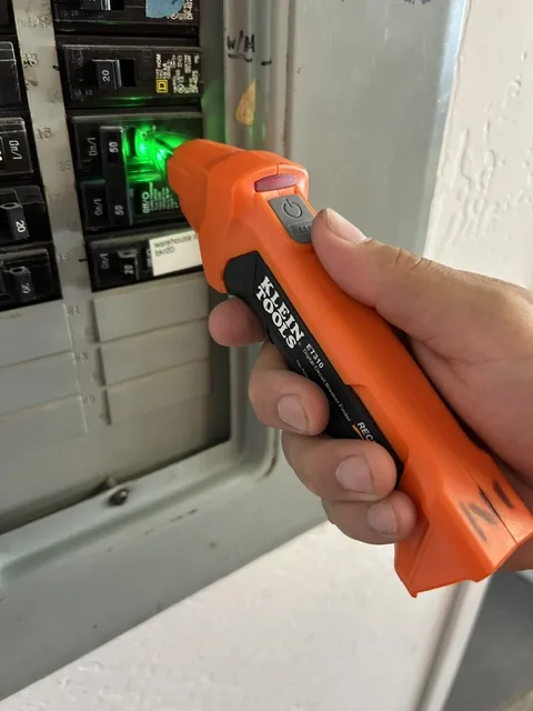 Technician using a non-contact voltage tester on a panel during a preventive maintenance visit, Arizona
