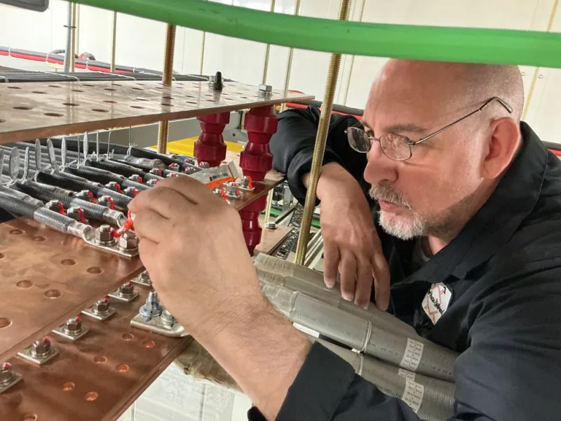New Phase technician working on DC copper bus bars and battery connections, Arizona